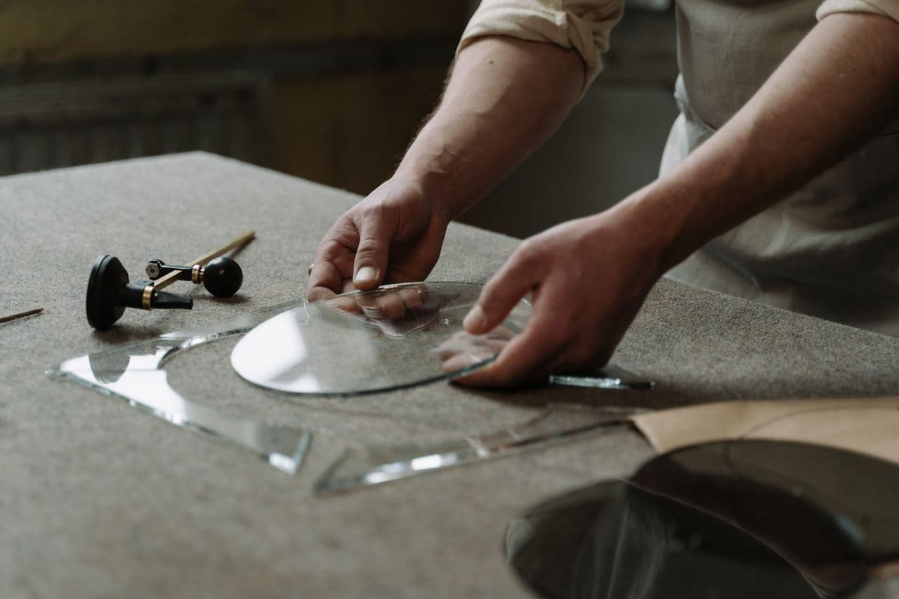 A person holding a round glass container representing glass manufacturing using silica and soda grains